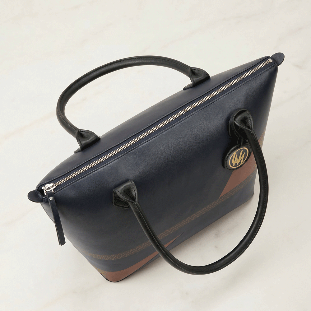 Designer leather tote bag angled view with black handles and structured base